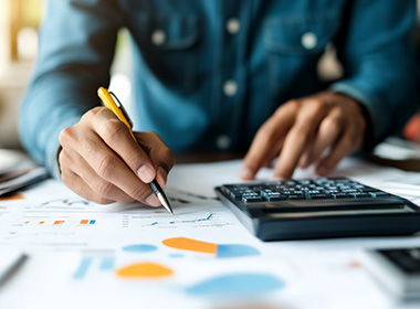 a-person-uses-a-calculator-while-working-on-financial-documents-with-graphs-and-charts-representing-the-detailed-analysis-necessary-for-financial-planning