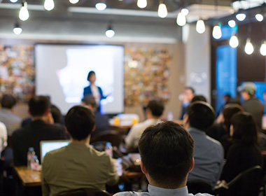 audience-watching-a-presentation-defocused-blurred-presenter-during-conference-meeting